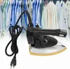 A black and silver electric steam iron with a yellow soleplate is shown in the foreground, with a blurred background of many hanging shirts in various shades of blue and white. Podgląd zdjęcia produktu