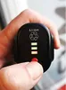 A hand holding a black battery pack with a power indicator. Produktbild-Vorschau