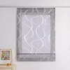 A gray sheer Roman blind with a white wavy stripe pattern hangs in front of a window, mounted on a curtain rail. A framed picture and a candle are visible on a dresser below the blind. Produktbild-Vorschau