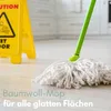 A mop with a green handle is on a light-colored wooden floor, with a yellow caution sign in the background. Produktbild-Vorschau