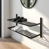 A two-tiered black metal shoe rack mounted on a white wall, holding a pair of black loafers and a pair of white sneakers. A circular mirror is visible in the upper background. Produktbild-Vorschau
