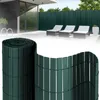 A roll of green privacy screen fencing is shown in the foreground, with a patio scene featuring lounge chairs and a modern house in the background. Produktbild-Vorschau