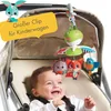 A baby is smiling in a stroller with a mobile toy hanging above. Voir les images du produit