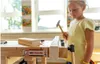 A young girl is using a mini workbench to hammer a nail into a piece of wood. Produktbild-Vorschau