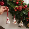 A hand is shown decorating a Christmas wreath with snowman ornaments. Podgląd zdjęcia produktu