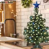 A small, decorated Christmas tree sits on a kitchen counter next to a sink and faucet, with string lights in the background. Produktbild-Vorschau