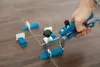 A hand is using a tool to adjust tile leveling wedges on a tiled floor. Náhľad obrázku produktu