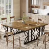 A dining room with a large wooden table and chairs, set for a meal. The kitchen is visible in the background. Produktbild-Vorschau