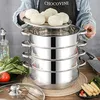 A person is holding a multi-tiered stainless steel steamer pot filled with steamed buns. Produktbild-Vorschau