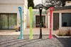 Four colorful outdoor showers are lined up in a modern backyard setting. Produktbild-Vorschau