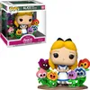 A Funko Pop! Deluxe figure of Alice from Disney's Alice in Wonderland, surrounded by anthropomorphic flowers. The figure is shown both in its packaging and displayed outside of it. Podgląd zdjęcia produktu