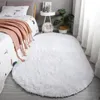 Weißer ovaler flauschiger Teppich auf hellem Holzboden neben einem Bett mit rosa Wurdecke Náhled obrázku produktu