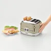 A hand is shown reaching for a cream-colored Ariete Vintage 4-slice toaster, with two slices of toast already popped up. To the left of the toaster is a plate with ingredients for a sandwich, including lettuce, tomato, cheese, and ham. Produktbild-Vorschau