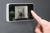A person's finger is pressing the screen of a digital door viewer mounted on a wall. Produktbild-Vorschau