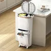 A white multi-compartment trash can with a drawer and pedal is shown in a kitchen setting, next to a kitchen island with a book and cup on it. Anteprima dell’immagine prodotto