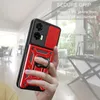 A hand holding a red and black phone case with a ring holder, with a blurred indoor background. Produktbild-Vorschau