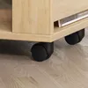 Close-up of the bottom of a wooden side table with black casters on a wooden floor. Produktbild-Vorschau