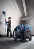 A man is using a wall sander connected to a vacuum cleaner in a room. Anteprima dell’immagine prodotto