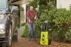 A man is pressure washing a car in a driveway. Produktbild-Vorschau