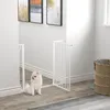 A white metal pet gate is installed in a hallway, with a small white dog sitting in front of it. Náhľad obrázku produktu