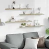 Four wooden shelves mounted on a white wall, decorated with various items. Náhľad obrázku produktu