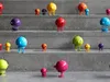 A collection of colorful, stylized toy figures are arranged on concrete steps. Produktbild-Vorschau
