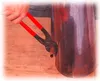 A person's hand is using a pair of pliers to work on a copper pipe next to a large copper cylinder. Náhľad obrázku produktu