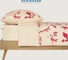 A close-up view of a bed with a pillow and fitted sheet, featuring a red berry pattern. Produktbild-Vorschau