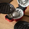 A close-up view of an open waffle maker with removable plates, resting on a wooden surface. Produktbild-Vorschau