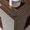 A close-up view of the corner of a dark brown wooden table, showing a felt pad attached to the corner. Produktbild-Vorschau