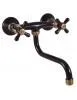 A black and bronze wall-mounted faucet with two cross handles and a curved spout. Anteprima dell’immagine prodotto