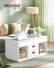 A white coffee table with storage is placed in front of a couch in a living room setting. Náhled obrázku produktu