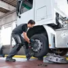 A mechanic is working on the wheel of a truck in a workshop. Podgląd zdjęcia produktu