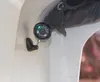 A close-up view of a small black security camera mounted on a white surface. Produktbild-Vorschau