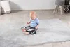A baby is sitting on a rug and playing with a black and white book. Náhled obrázku produktu