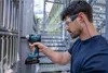 A man is using a Bosch cordless impact wrench on a metal structure outdoors. Voir les images du produit