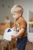 A young boy is holding a white potty in a room. Náhľad obrázku produktu