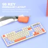 A keyboard with colorful keys is shown on a light blue surface, with a book and an orange accessory in the background. Text overlays describe the keyboard's features. Produktbild-Vorschau