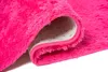 A close-up view of a pink fluffy rug, showing the texture and the underside with anti-slip dots. Produktbild-Vorschau