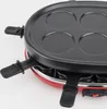 A close-up view of a red and black raclette grill with four circular indentations on its top surface. Produktbild-Vorschau