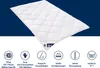A white quilted duvet is displayed diagonally against a blue background, with several circular icons and text below detailing product features. Produktbild-Vorschau