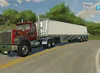 A red and gray Mack truck pulling a white trailer drives down a paved road with trees and a house in the background. Náhled obrázku produktu