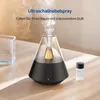 A modern aroma diffuser emitting mist, placed on a wooden table next to a small bottle of essential oil. Produktbild-Vorschau