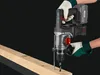 A person wearing gloves is using a cordless hammer drill to drill into a piece of wood. Produktbild-Vorschau