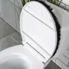 A close-up view of the lid of a toilet with a black brush attached to the rim. Produktbild-Vorschau