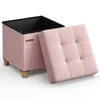 A pink storage ottoman with its lid open, showing the black interior and resting on wooden legs. Náhled obrázku produktu