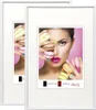 Two white picture frames are shown, each with a different image inside. The left frame shows a partial view of a woman holding macarons. The right frame shows a close-up of a woman's face with macarons covering her eyes and hands. Produktbild-Vorschau