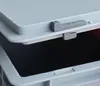 A close-up view of a gray plastic latch mechanism on a light gray storage container lid. Produktbild-Vorschau