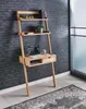 A wooden ladder desk with shelves and a drawer, set against a dark brick wall and next to a glass door. Voir les images du produit