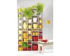 A white shelving unit filled with various colored plant pots, some containing plants. A wooden bench with red yarn is in the foreground. Anteprima dell’immagine prodotto